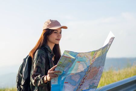 women asian with bright backpack looking at a map. View from back of the tourist traveler on...