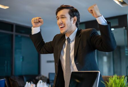Asian businessmen Success and winning concept - happy team with raised up hands celebrating the breakthrough and achievementsの写真素材
