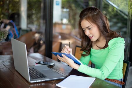 Asian businesswomen smiling and using notebook for analysis documents and graph financial diagram...