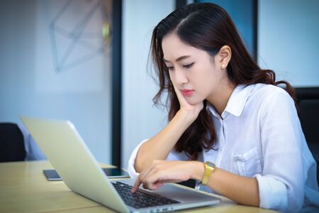 Asian business women using notebook and  serious and headache for workingの写真素材