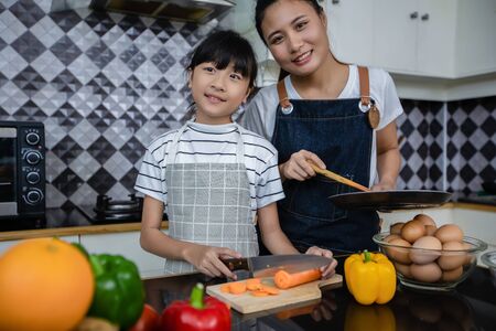 Asian families are cooking  and parents are teaching their daughters to cook in the kitchen at home. Family activities on holidays and Happy in recreation conceptの写真素材