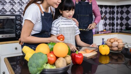 Asian families are cooking  and parents are teaching their daughters to cook in the kitchen at home. Family activities on holidays and Happy in recreation conceptの写真素材