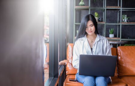Asian businesswomen are using notebook computers for working from home.She is smile happy and enjoys working.の写真素材