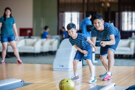 Father teaching son and family play bowling at bowling club on relax time, family activity on holiday concept の写真素材