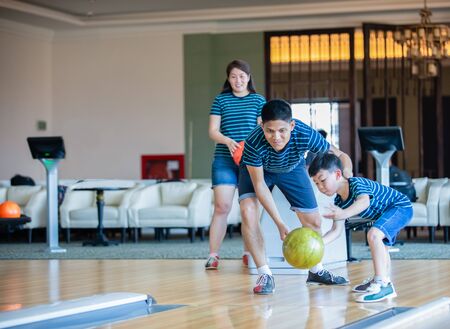Father teaching son and family play bowling at bowling club on relax time, family activity on holiday conceptの写真素材
