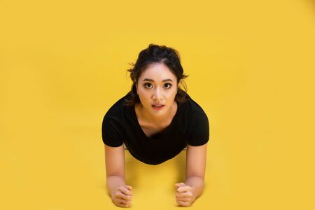 Smile happy Beautiful portrait young Asian woman stretching exercise workout on yellow background, fitness sport girl aerobic and healthy concept.の写真素材