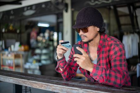 Asian hipster man  are holding credit cards and using  mobile phones for online shopping.の写真素材