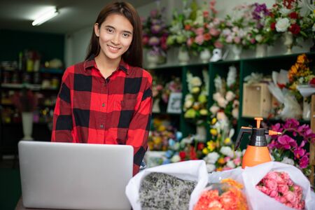 Asian women florists using notebook for working and smiling in flower shopの写真素材