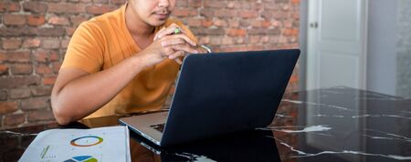Asian man uses a notebook computer and works hard and meeting at home and he is stressed and...