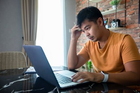 Asian man uses a notebook computer and works hard and meeting at home and he is stressed and Headache.の写真素材