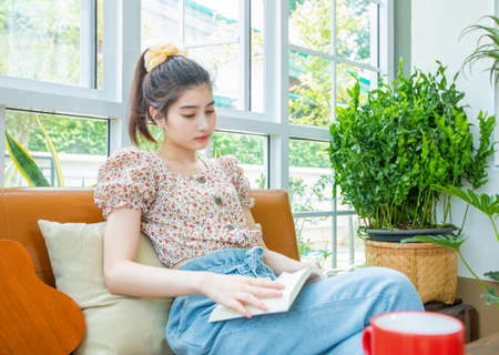 Asian women use their notebook computers to study and practice playing ukulele on the internet at home.の写真素材