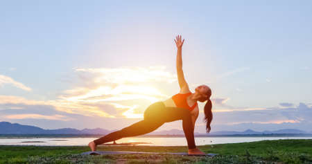 Asian women are exercising with yoga outside near the river in the evening