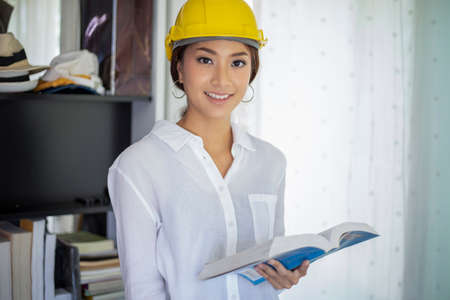 Asian women engineering inspecting and working and holding blueprints at home office