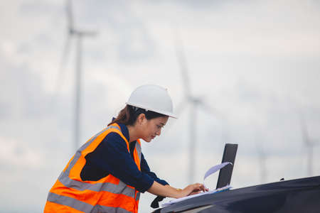 Women engineer using tablet for working on site at wind turbine farm