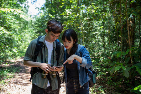 Asian Group of young people Hiking with friends backpacks walking together and looking map and...