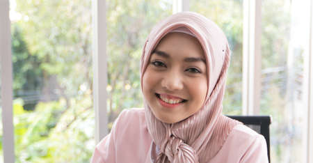 Happy Muslim business woman in traditional clothing smiling and working in office
