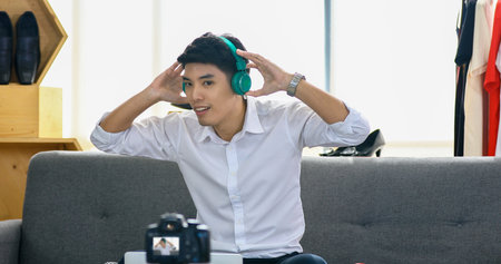 Asian man blogger broadcasting a video for selling product online such as Hats, shoes, headphones,...