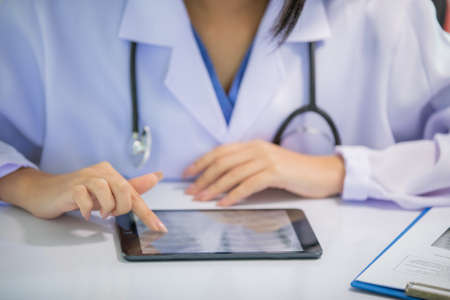Asian women doctor  working and analyzing x-ray images  at  hospital office