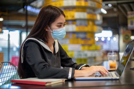 Asian women wearing a mask and she working and studying online with their notebook computers.の写真素材