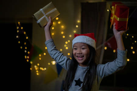Asian Happy family with daughter in Santa hats gathered together on Christmas time and enjoy gifts boxの写真素材