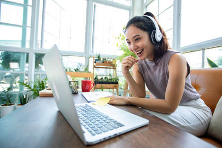Asian businesswomen is using notebook computers and wear headphones for online meetings and working...
