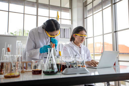 Medical Research and Scientists are working with a microscope and a tablet and Test Tubes, Micropipette and Analysis Result in a laboratory.の写真素材