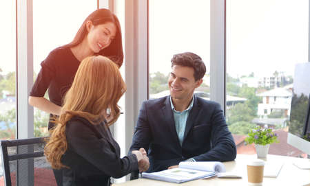 Business people shaking hands and smiling their agreement to sign contract and finishing up a...