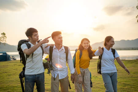 A group of Asian friends backpacking bag and walking for picnic and camping near lakeの写真素材