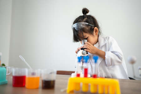 Asian children in lab coat using a microscope for a science experiment in homeschool laboratoryの写真素材