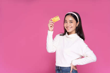 Beautiful Asia women smile and holding credit card purchase online shopping and excited with success payment on isolated pink backgroundの写真素材