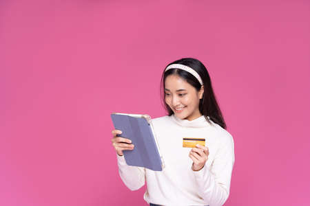 Beautiful Asia women smile use tablet and credit card purchase online shopping and excited with...