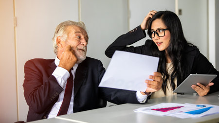 elderly Businessman and business woman sitting in a meeting and checking documents and notebooks on a desk in a meeting room.の写真素材