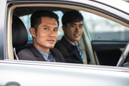 Two business men are driving and looking out of the car window.の写真素材