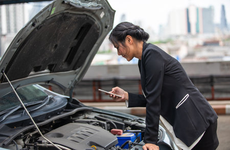 A businesswoman is calling for help as her car breaks down on the side of the road.の写真素材