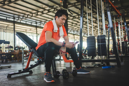 young male playing phone and listening to music after exercise in fitness.の写真素材