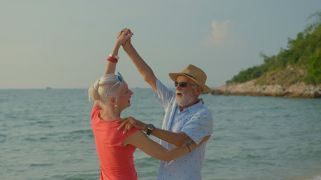 Two elderly men and women dancing at the beach on their summer vacation and they smile and enjoy their day off.の写真素材