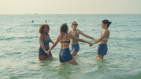 A group of teenage girls run and play at the beach for their summer vacation and they smile and enjoy their vacation.の写真素材