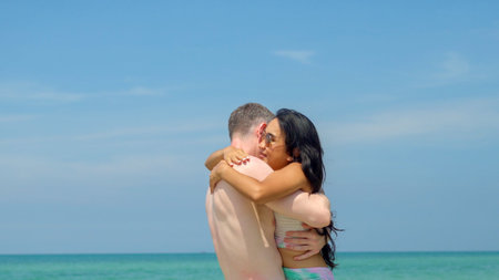 A couple hugs and kisses on the beach on their summer vacation and they smile and are happy on vacation.の写真素材