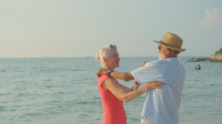 Two elderly men and women dancing at the beach on their summer vacation and they smile and enjoy their day off.の写真素材