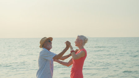 Two elderly men and women dancing at the beach on their summer vacation and they smile and enjoy their day off.の写真素材
