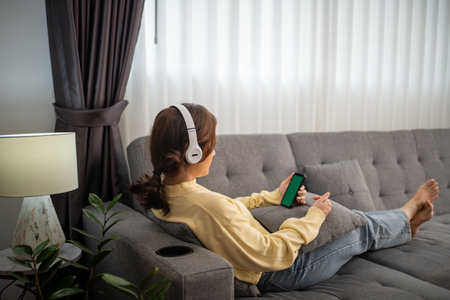 Woman wearing headphones and listening to music and singing happy at home on vacation.の写真素材