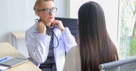 Asian woman patient sitting with doctor about her illness and showing x-ray results with blood pressure and heart rate measurement with stethoscopeの写真素材