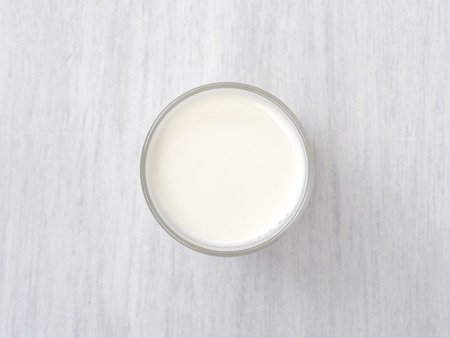 Glass of milk on white wooden floorの写真素材