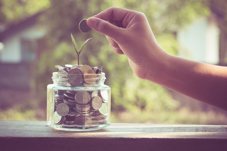 hand putting money coins  with filter effect retro vintage styleの写真素材