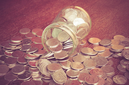 Coins spilling out of a glass bottle with filter effect retro vintage styleの写真素材
