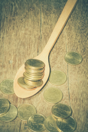 Coins in a wooden spoon with filter effect retro vintage styleの写真素材