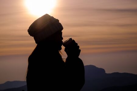 Drinking a warm drink at sunsetの写真素材