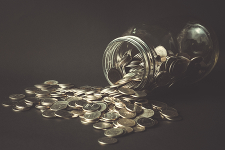 Coins spilling out of a glass bottle with filter effect retro vintage styleの写真素材