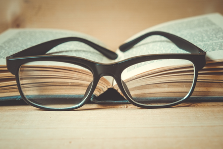Old books and glasses on a wooden table with filter effect retro vintage styleの写真素材
