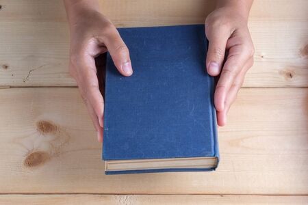 Hands hold book on wood table
